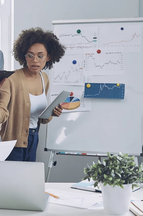 Woman standing pointing at whiteboard with research